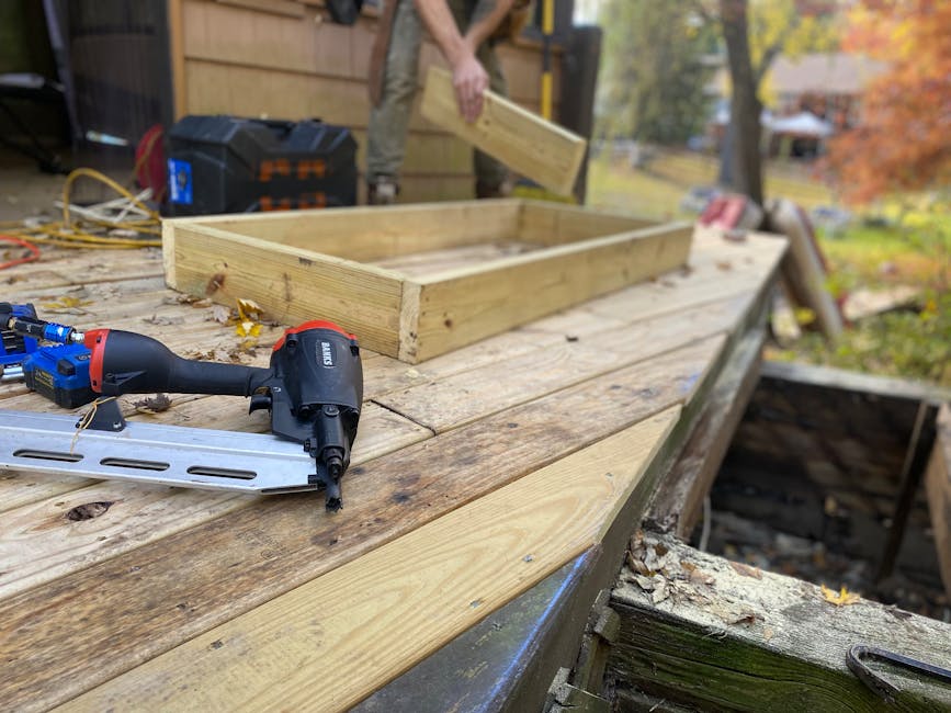 Close-up of carpentry work on a deck with a nail gun and wooden frame under construction.