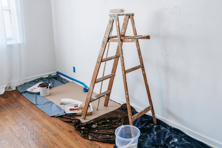 A room with a stepladder and painting tools, showcasing a renovation process.