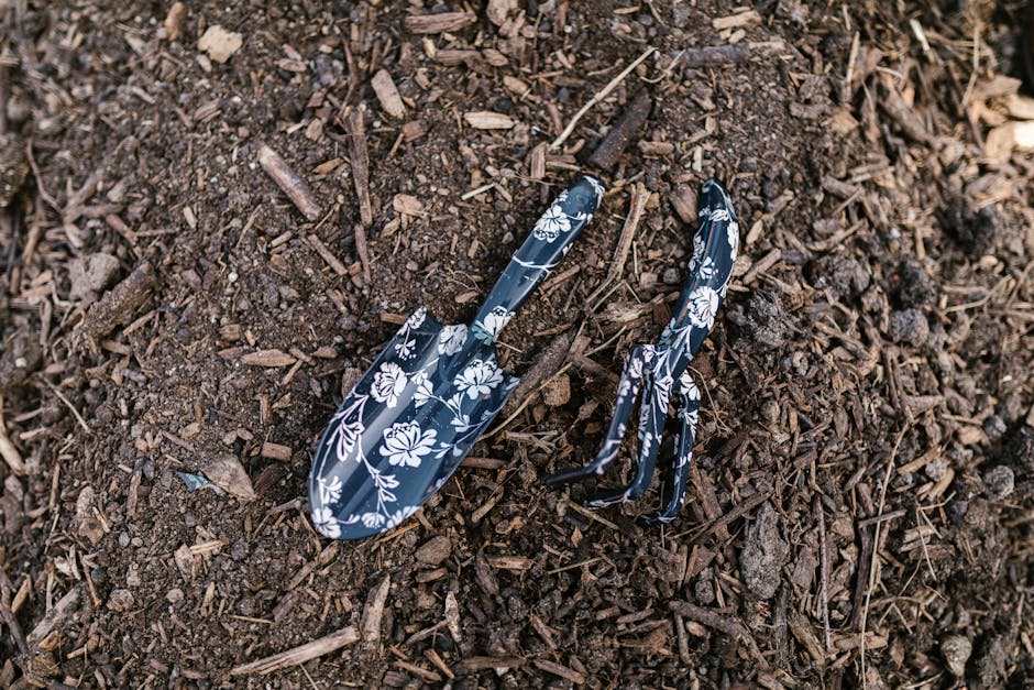 Close-up of floral patterned rake and shovel resting on soil, ideal for gardening themes.